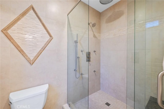 bathroom featuring an enclosed shower, toilet, and tile walls