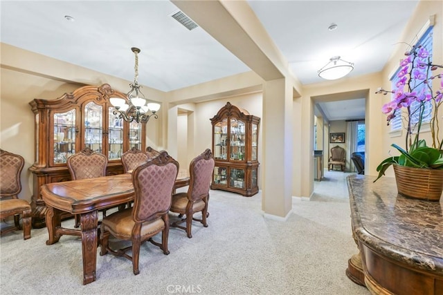 dining space featuring a healthy amount of sunlight, light colored carpet, and an inviting chandelier