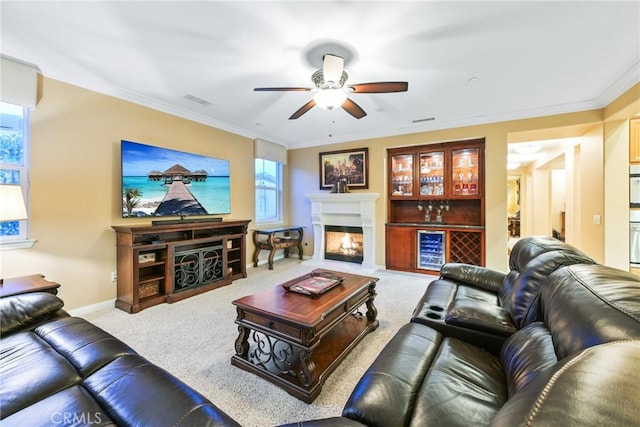 living room featuring ceiling fan, light colored carpet, crown molding, and bar area