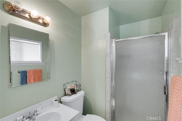 bathroom featuring toilet, a shower with door, and sink