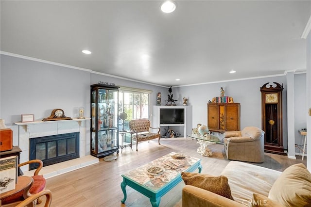 living room with a tile fireplace, crown molding, and light hardwood / wood-style flooring