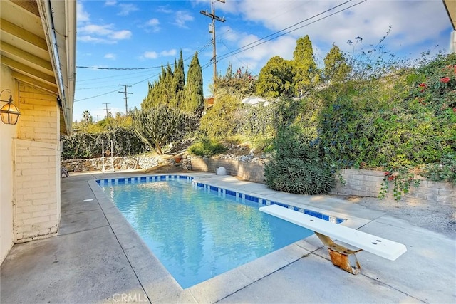 view of swimming pool with a diving board and a patio area