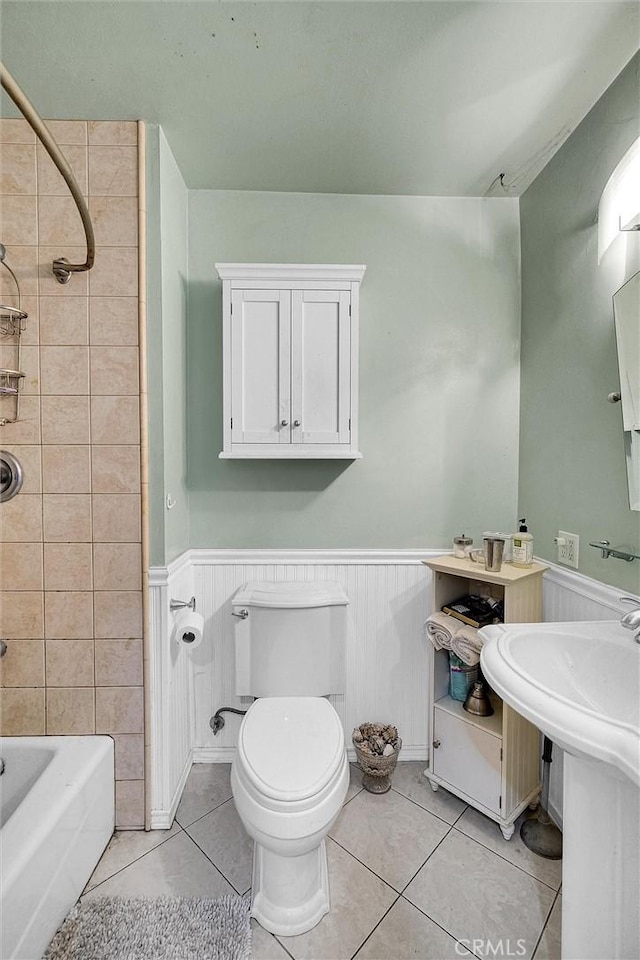 bathroom featuring toilet, tiled shower / bath, and tile patterned flooring