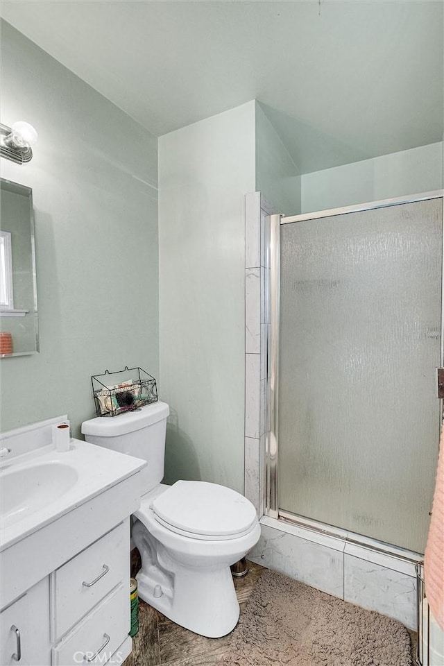 bathroom with toilet, vanity, and a shower with door