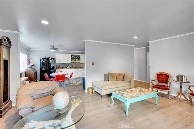 living room with ceiling fan, crown molding, and light wood-type flooring