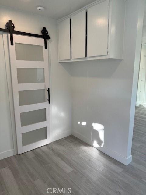 clothes washing area featuring a barn door and light hardwood / wood-style flooring