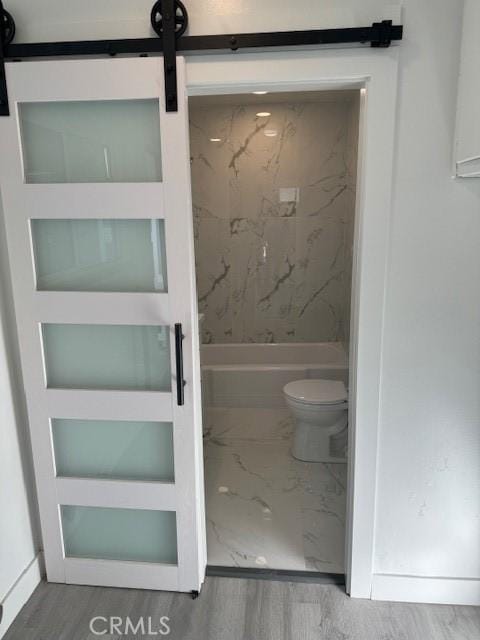 bathroom featuring hardwood / wood-style flooring, toilet, and tiled shower / bath