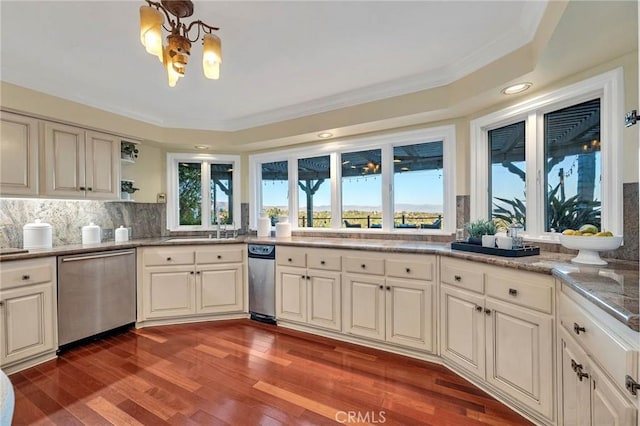 kitchen featuring backsplash, ornamental molding, wood-type flooring, a notable chandelier, and dishwasher