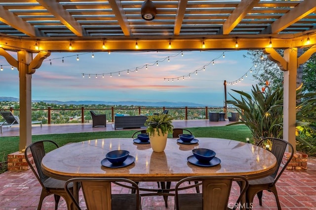 patio terrace at dusk featuring a mountain view, a pergola, and a lawn