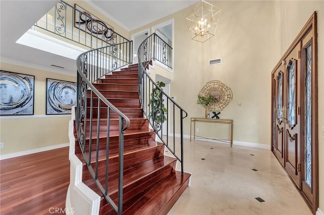 entrance foyer featuring hardwood / wood-style floors, a notable chandelier, ornamental molding, and a high ceiling