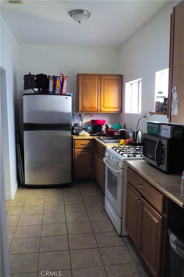 kitchen featuring appliances with stainless steel finishes, light tile patterned floors, and sink