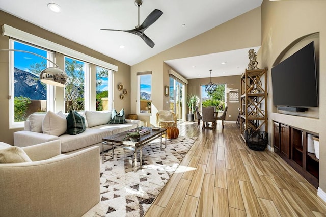 living room with lofted ceiling, ceiling fan, and light wood-type flooring