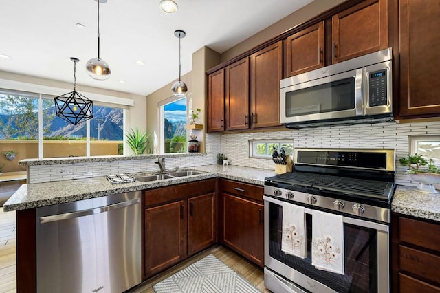 kitchen with stainless steel appliances, light stone counters, light hardwood / wood-style flooring, pendant lighting, and decorative backsplash