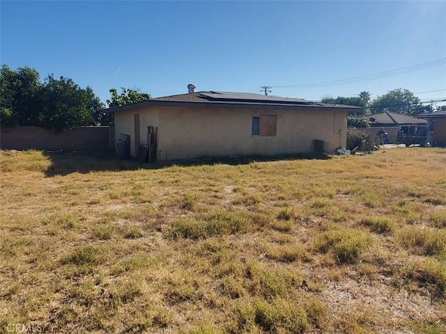 view of side of property featuring a yard and solar panels