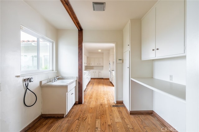 corridor with light wood-type flooring and sink