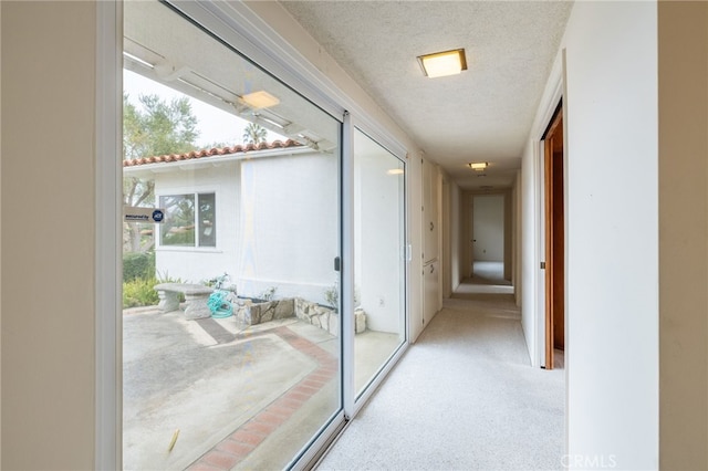 corridor featuring a textured ceiling and light colored carpet