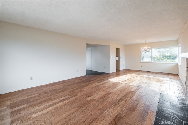 unfurnished room featuring a chandelier, wood-type flooring, and a textured ceiling