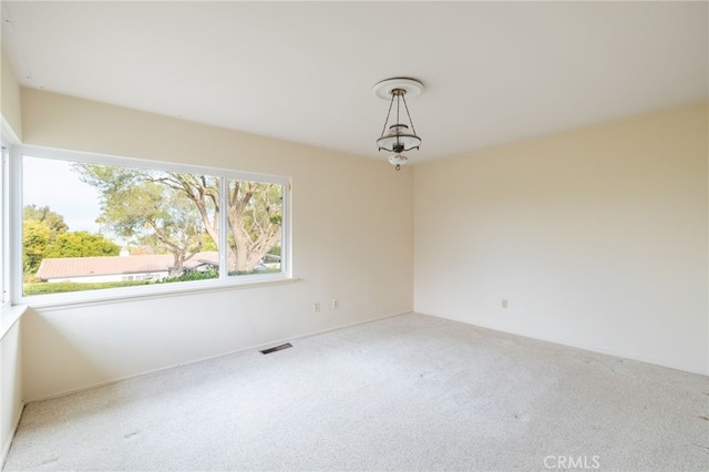 spare room with carpet and a chandelier