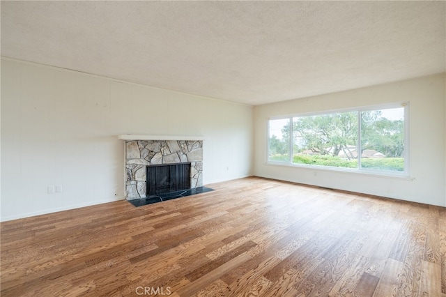 unfurnished living room featuring a fireplace, wood-type flooring, and a textured ceiling