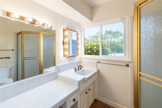 bathroom with hardwood / wood-style flooring, vanity, toilet, and a shower with door