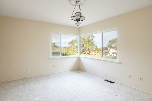 spare room featuring carpet and a chandelier