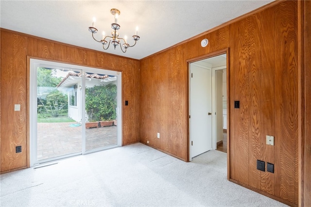 carpeted empty room with wood walls, a textured ceiling, and a notable chandelier