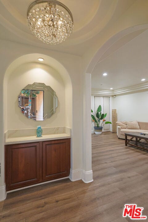 interior space with a tray ceiling, hardwood / wood-style floors, a notable chandelier, and vanity