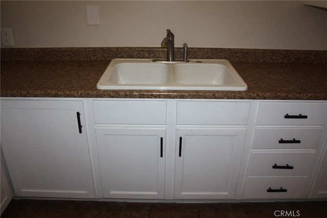 kitchen with dark countertops, white cabinets, and a sink