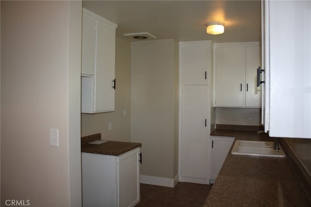 kitchen featuring white cabinets, dark tile patterned flooring, and sink