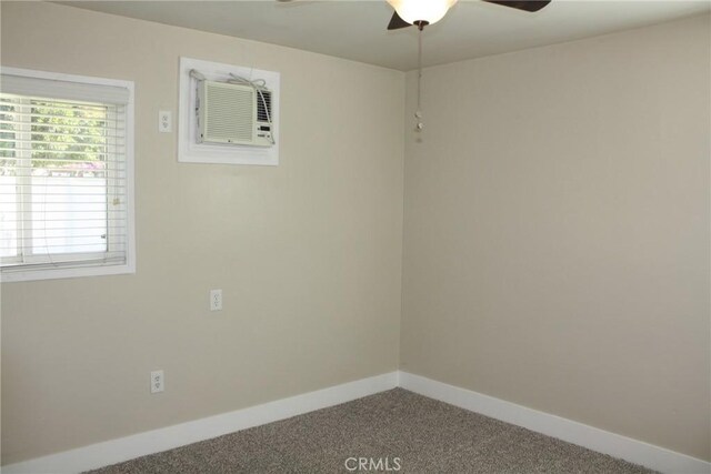 carpeted empty room featuring an AC wall unit, ceiling fan, and baseboards