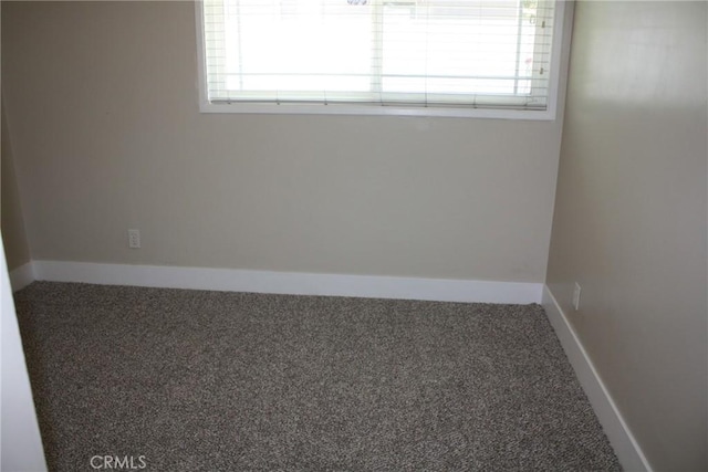 carpeted spare room featuring baseboards