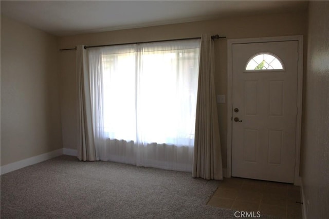 carpeted foyer with tile patterned flooring and baseboards