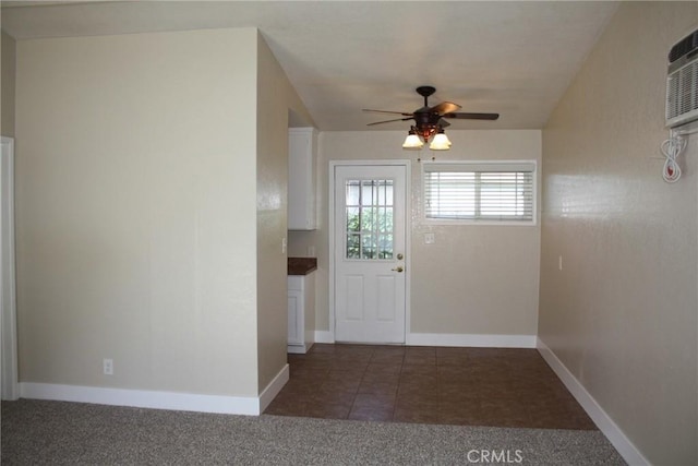 doorway featuring ceiling fan, carpet, tile patterned flooring, and baseboards