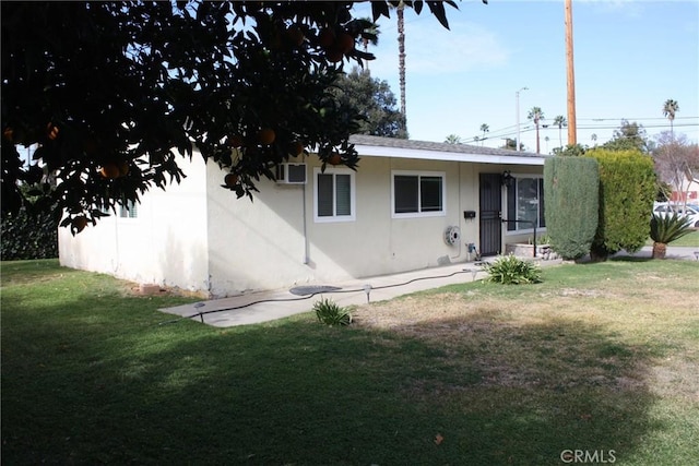 rear view of property featuring a lawn and stucco siding