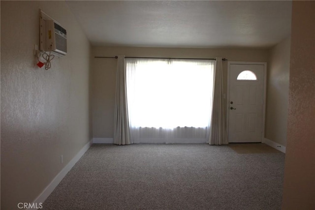 carpeted empty room with plenty of natural light, baseboards, and a wall mounted air conditioner