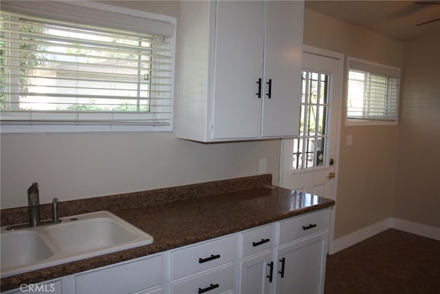 kitchen featuring dark tile patterned floors, sink, white cabinets, and dark stone counters