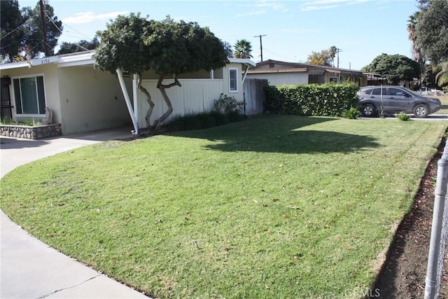 exterior space featuring a yard, a carport, driveway, and stucco siding