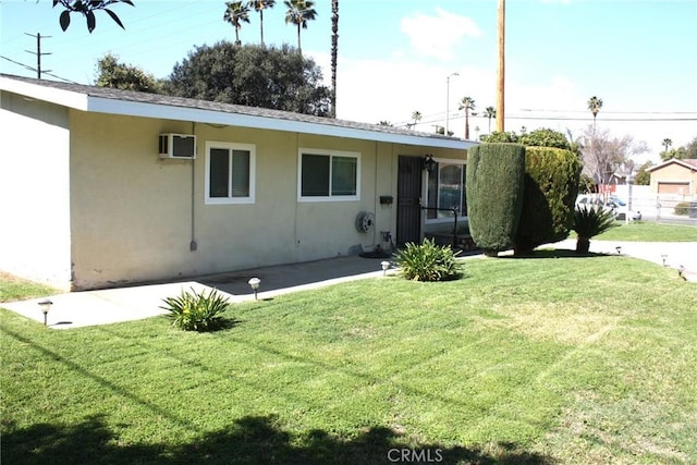 view of front of house with a front yard, a wall unit AC, and stucco siding