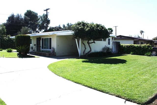 ranch-style house with a carport, stucco siding, concrete driveway, and a front yard