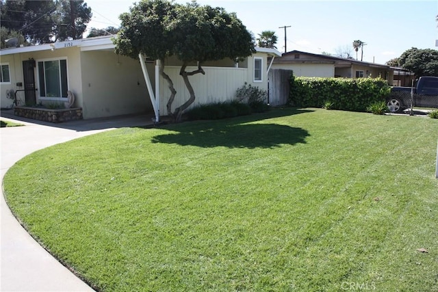 view of yard with concrete driveway, a carport, and fence