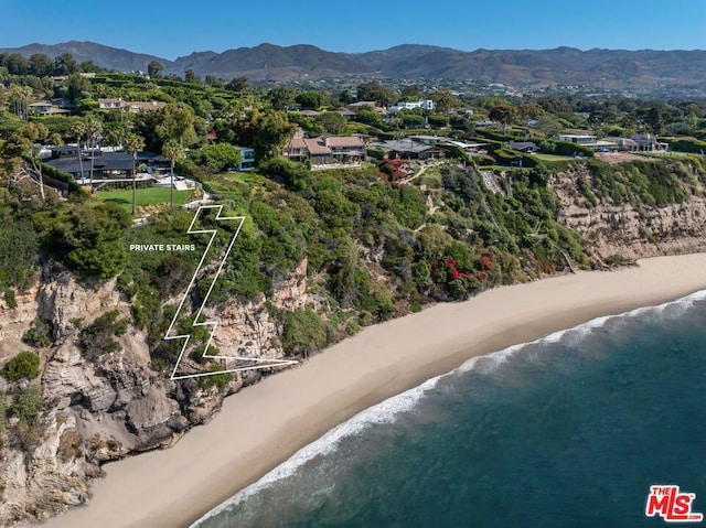 drone / aerial view featuring a water and mountain view and a view of the beach