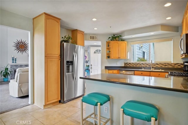 kitchen with backsplash, sink, a breakfast bar area, light tile patterned floors, and stainless steel appliances