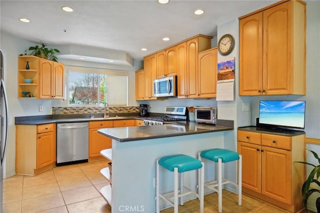 kitchen with a breakfast bar, sink, light tile patterned floors, and stainless steel appliances