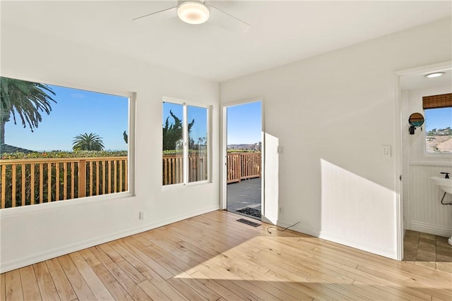 spare room with ceiling fan, a wealth of natural light, and light wood-type flooring