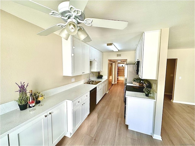 kitchen with white cabinetry, sink, ceiling fan, black dishwasher, and light wood-type flooring