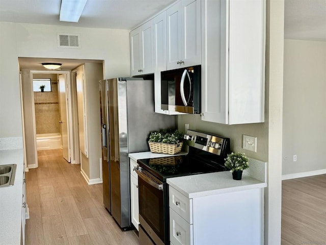 kitchen featuring light wood-type flooring, stainless steel appliances, and white cabinetry