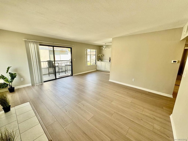 interior space featuring ceiling fan, light wood-type flooring, and a textured ceiling