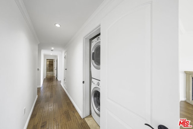 washroom featuring wood-type flooring, crown molding, and stacked washer and clothes dryer