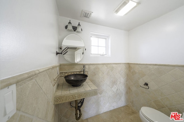 bathroom featuring sink, tile patterned flooring, tile walls, and toilet