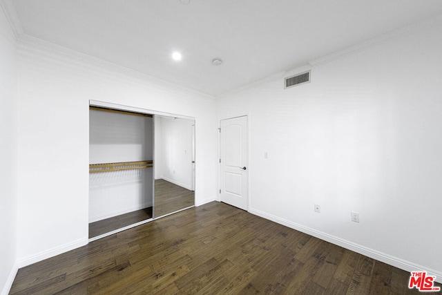 unfurnished bedroom featuring dark hardwood / wood-style flooring, ornamental molding, and a closet